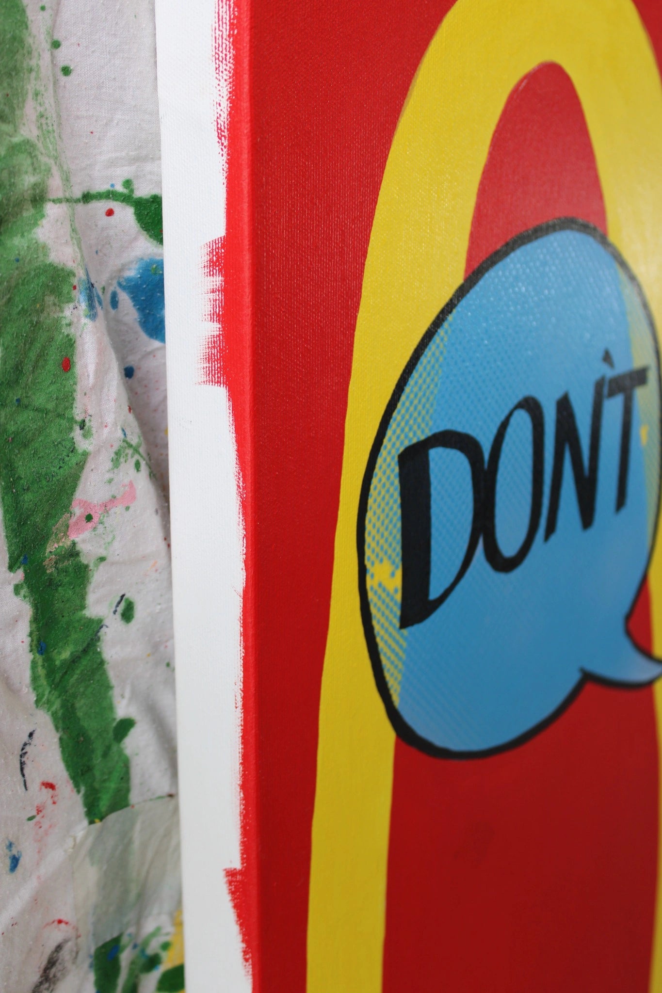 "Side perspective of 'DON'T' by Let Z Be Studio, highlighting the textured layers of acrylic, spray paint, and screen printing on canvas."