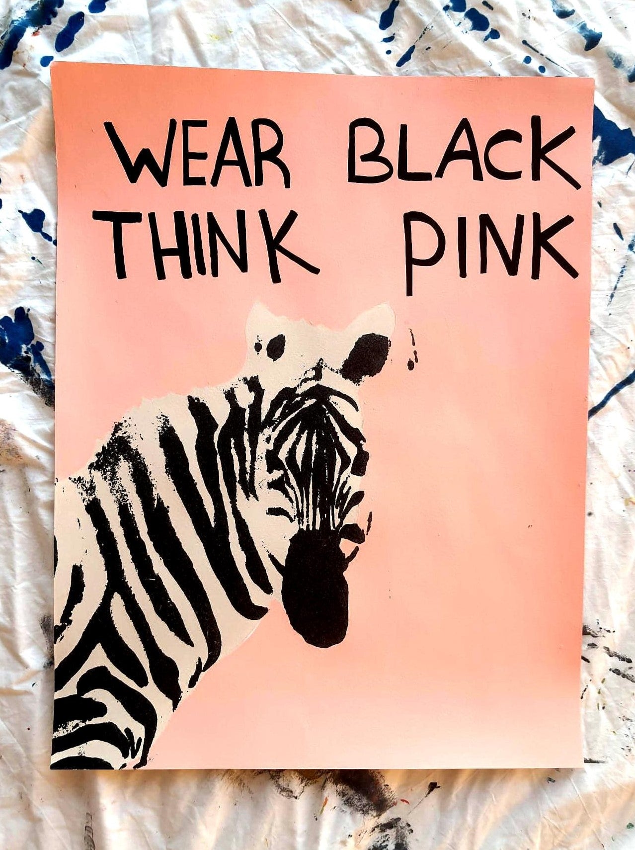 "Zebra artwork on pink-orange background with the text 'Wear Black Think Pink' in bold black letters."