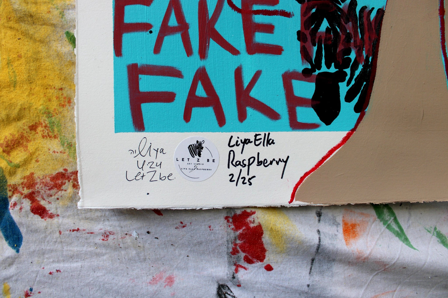 "Close-up of the signature and edition number on the bottom left corner of Liya Ella Raspberry’s painting from the expanded 'It Came Out a Bit Sad, So I Put on a Smile' series. The image shows the artist's signature, the 'Let Z Be' studio logo, and the unique edition number of the artwork."

