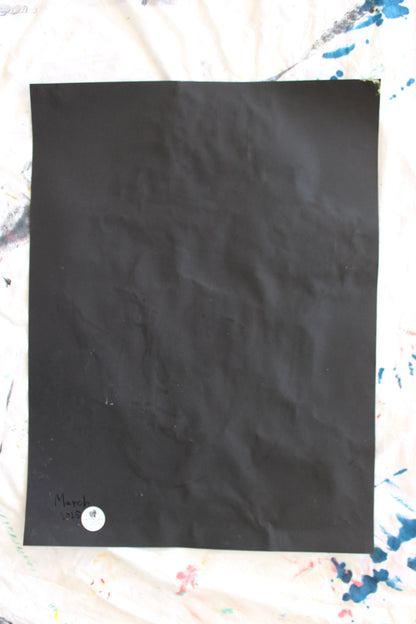 "The back of a black paper with slight creases, featuring the date 'March 2025' written in coal and a 'Let Z Be' logo sticker at the bottom corner, marking the authenticity of the artwork."







