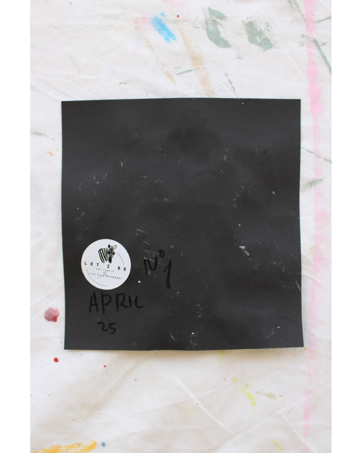 "Back of artwork showing signature, date, and Let Z Be logo sticker on black paper."

