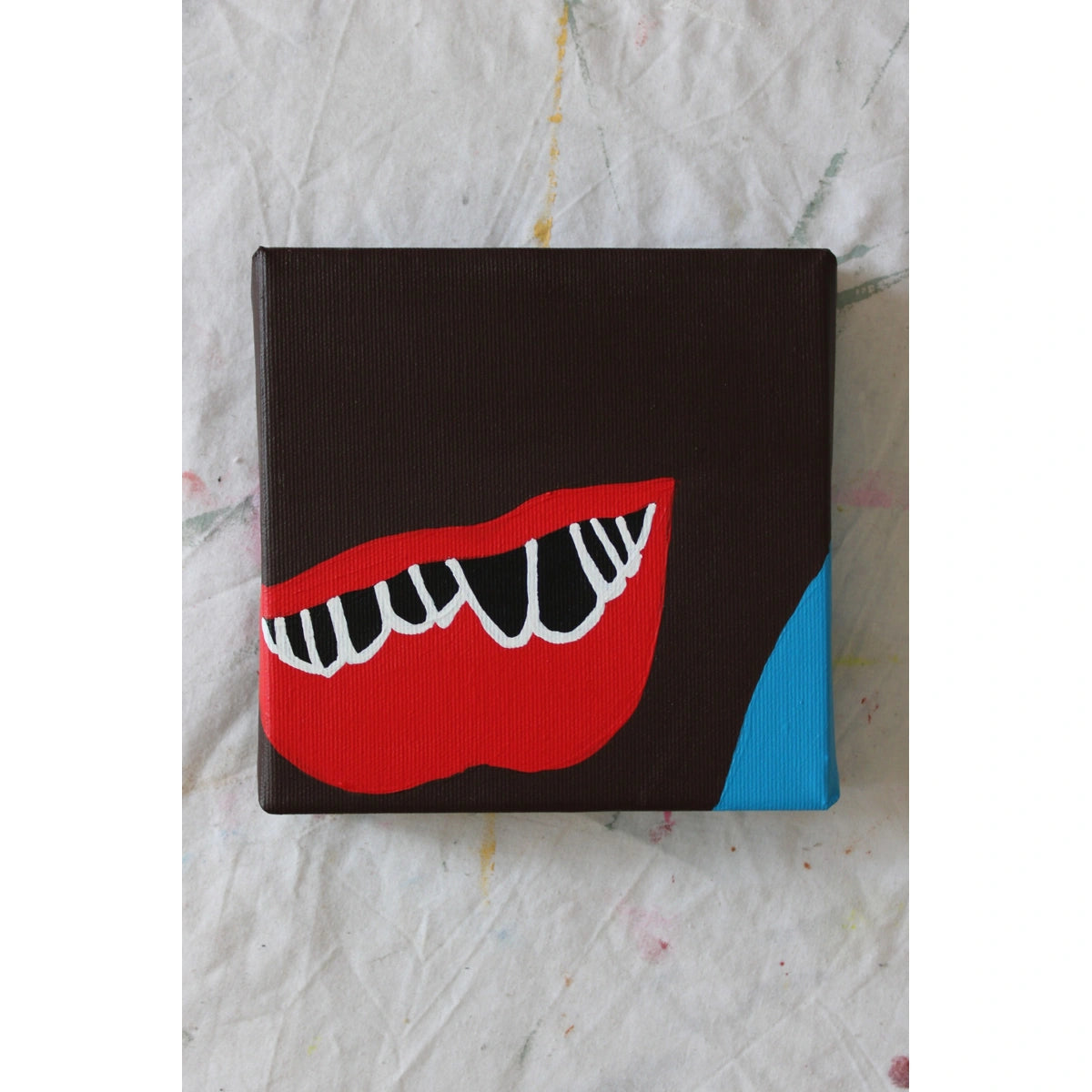 "Contemporary painting of red lips with exaggerated white teeth on dark brown canvas and a vivid blue corner — acrylic on canvas by Liya Ella Raspberry, PLAY ME. BOY. series, 2025."