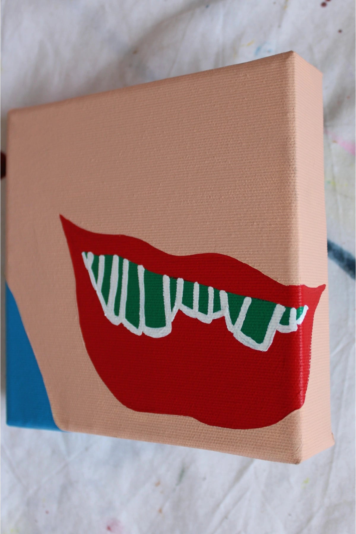 "Pop art side view of red lips flashing green-striped teeth — a cheeky nod to Maccabi Haifa. Acrylic on canvas by Liya Ella Raspberry, June 2025."